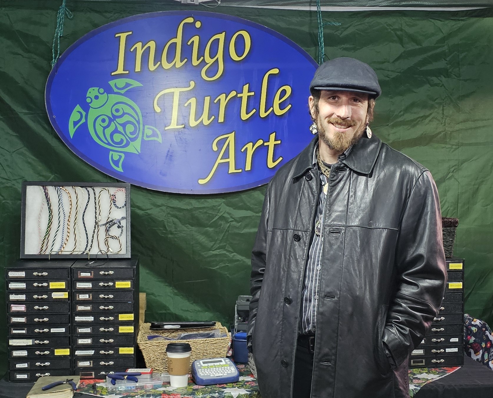 Joseph Evans stands at a merchant site with a sign that reads "Indigo Turtle Art"