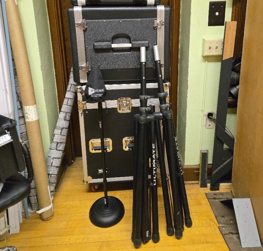 A stack of electronics storage cases and microphone stands.